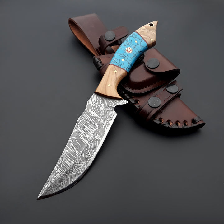 Decorative knife with a wooden handle and blue inlay, attached to a leather sheath on a dark background.