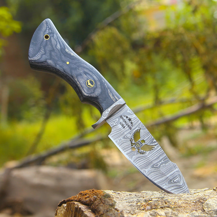 Decorative knife with a wooden handle on a wooden stump against a blurred natural background