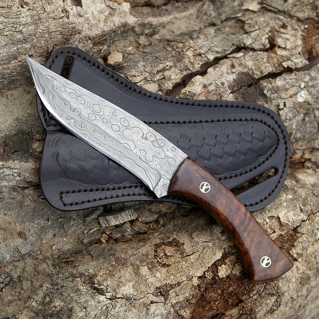 Knife with wooden handle and leather sheath on a textured surface