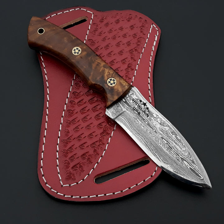 Knife with wooden handle and silver blade in a red leather sheath on a dark background